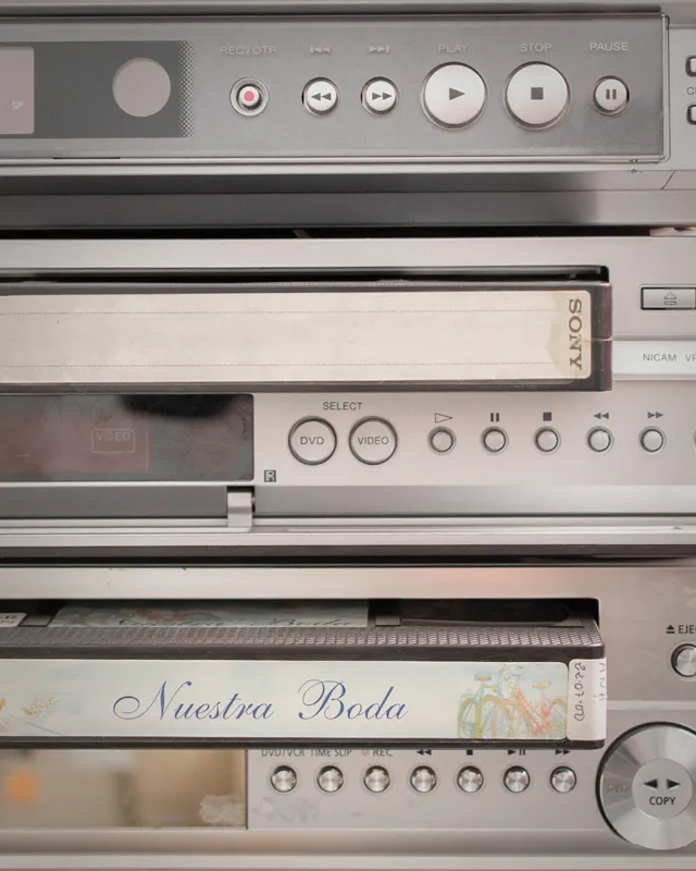 Cinta VHS etiquetada "Nuestra Boda" junto a reproductores de vídeo apilados